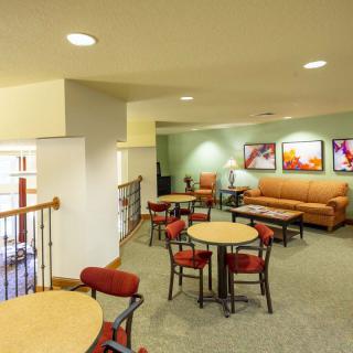 A comfortable lounge area with tables, chairs, and a sofa, decorated with artwork on the walls.