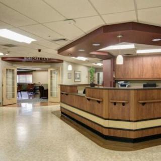 A well-lit lobby with a wooden reception desk and seating area.