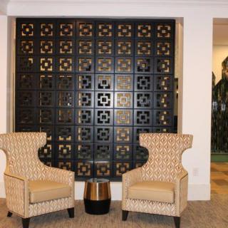 A stylish lounge area featuring two patterned chairs and a decorative black screen.
