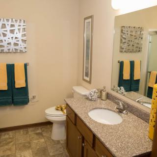 A modern bathroom interior with a double sink, mirror, and colorful towels.