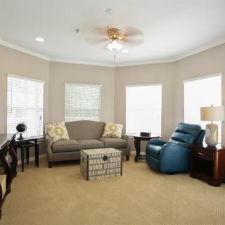 A cozy living room with a sofa, recliner, and multiple windows letting in natural light.
