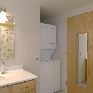 A bathroom with a mirror, sink, and a stacked washer and dryer unit.
