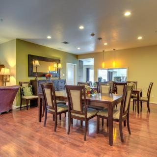 A spacious dining room with a wooden table and chairs, featuring warm lighting and wood flooring.