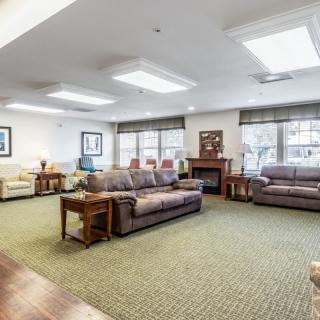 A spacious living room with multiple sofas and natural light from large windows.