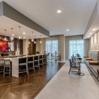 A modern kitchen and dining area featuring a bar with stools and elegant pendant lighting.