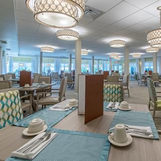 An elegant restaurant dining area with neatly arranged tables and stylish chandeliers.