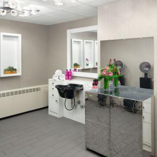 A modern salon interior with a hairdressing station, sink, and decorative flowers.