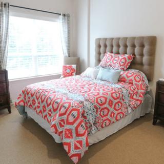 A cozy bedroom with a colorful geometric patterned bedspread and ample natural light.