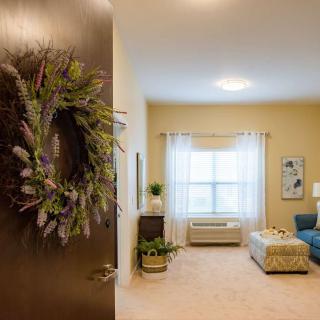 A cozy living room with a wreath on the door, featuring comfortable furniture and soft lighting.