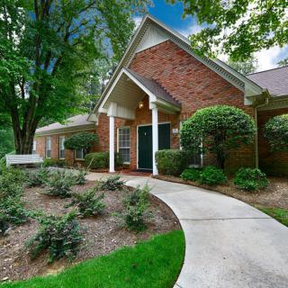 A charming brick house with a landscaped garden and a curved pathway leading to the entrance.