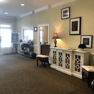 A warmly decorated lobby with chairs, a cabinet, and framed artwork on the walls.