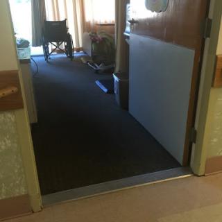 A view of an open door leading into a hospital room, with a wheelchair visible in the background.