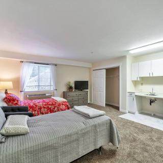 Spacious bedroom with two beds, a TV, and a kitchenette.