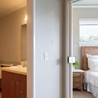 View of a bedroom through an open door with an adjacent bathroom.