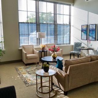 A modern living room with large windows allowing natural light, featuring comfortable furniture and stylish decor.