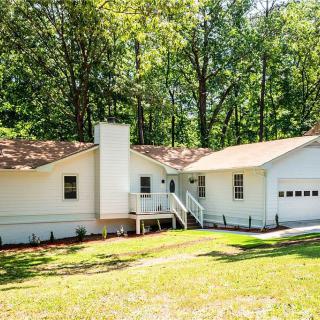 A cozy white house nestled among trees with a spacious front yard.