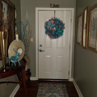 A cozy entrance featuring a vibrant wreath and artistic wall decorations.