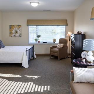 A cozy bedroom with a bed, armchair, and decorative elements.