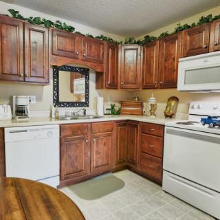 A cozy kitchen with wooden cabinets, featuring a gas stove, dishwasher, and various appliances.