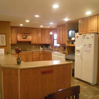 A spacious kitchen with wooden cabinets, a large countertop island, and a refrigerator.