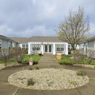 A quaint house with a garden and pathway leading to the entrance on a cloudy day.