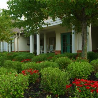 A scenic view of a house with a well-maintained garden featuring lush bushes and vibrant flowers.