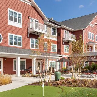 A modern brick residential building with balconies and landscaped surroundings.