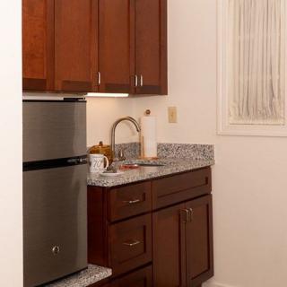 A small kitchen area with wooden cabinets, a granite countertop, and stainless steel appliances.
