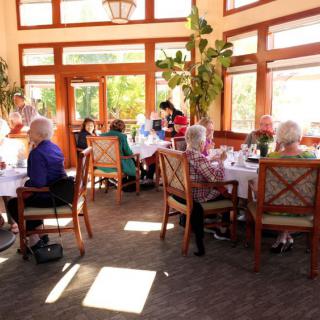 A group of seniors enjoying a meal and socializing in a bright, sunlit restaurant interior.
