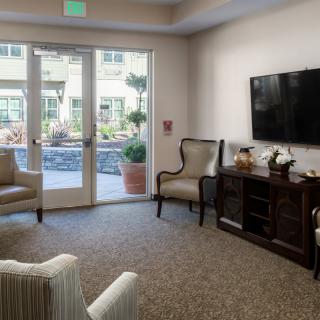 A cozy living room with comfortable seating, a television, and large patio doors leading outside.