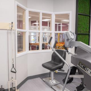 A well-equipped fitness center featuring exercise machines and a view through large windows.