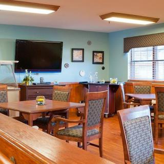 A dining room with wooden furniture and a television mounted on the wall.
