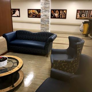 A cozy lounge area featuring a blue sofa and patterned chairs, complemented by a coffee table and artistic photographs on the walls.