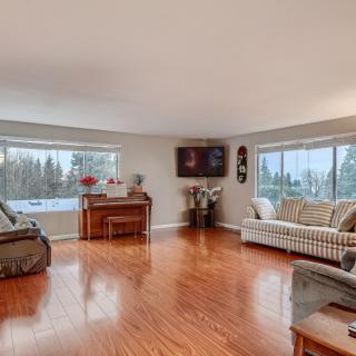 Spacious living room with hardwood flooring and large windows letting in natural light.