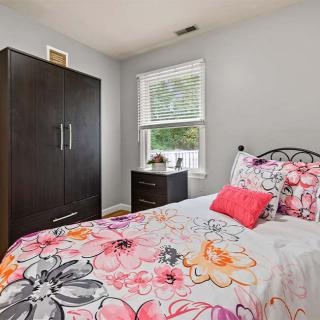 A cozy bedroom with floral bedding, a wardrobe, and a window.