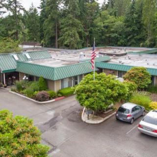 Aerial view of a building with a parking lot surrounded by trees.