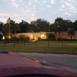 A well-lit building with a flagpole and surrounding trees at dusk.