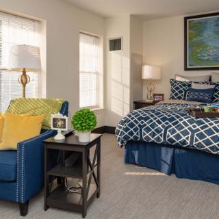 A cozy bedroom with stylish decor, featuring a comfortable armchair and patterned bedding.