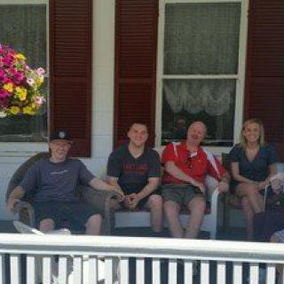A group of people sitting on a porch with hanging flowers nearby.
