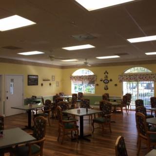 A cozy dining room with several tables and chairs, decorated with wall hangings and illuminated by overhead lights.