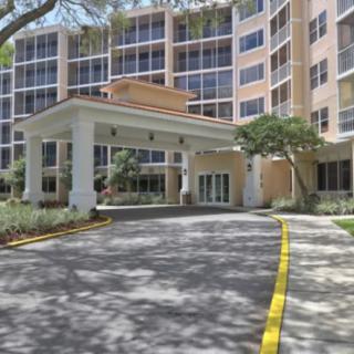 A residential building entrance with a driveway and surrounding trees.