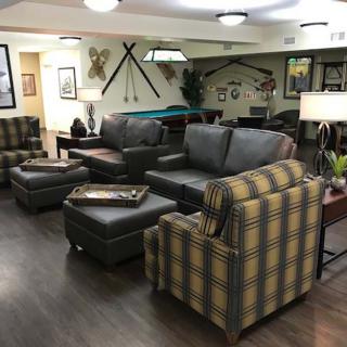 A cozy living space featuring a mix of sofas and armchairs, with a pool table and framed artwork in the background.