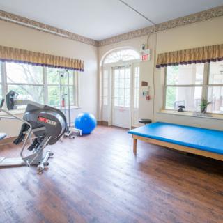 A bright and spacious home gym featuring a stationary bike, exercise ball, and a workout mat, ideal for fitness enthusiasts.