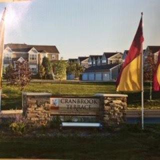 Entrance to a residential neighborhood featuring flags and a stone wall sign.