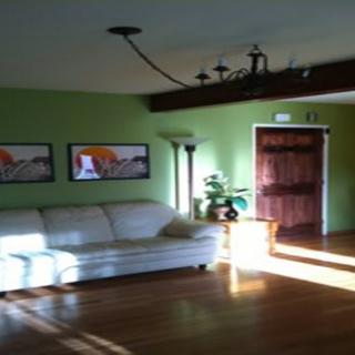 A cozy living room with a white sofa, green walls, and wooden floors.