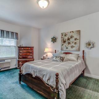 A cozy bedroom with a wooden bed, decorative wall art, and a warm table lamp.