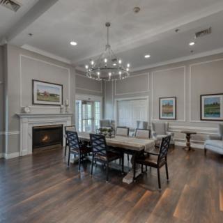 A modern dining room with a chandelier, hardwood flooring, and a fireplace.