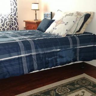 A neatly made bed with blue striped bedding and decorative pillows in a cozy bedroom setting.