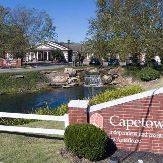 Entrance to Capetown community with a sign, pond, and landscaping.