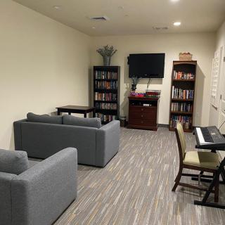 A cozy living room with sofas, bookshelves, a piano, and a television.